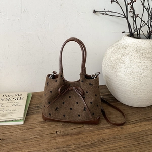 Detail of retro polka dot tweed tote with leather bow on a rustic wooden background
