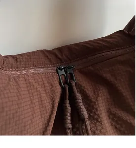 Detail of smooth double metal zippers with thick rope pulls on brown textured fabric bag
