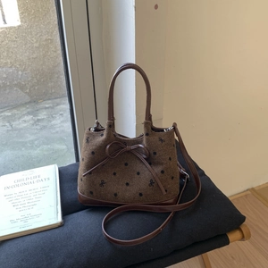Detailed macro view of brown polka dot woven fabric and leather bow on a tote bag