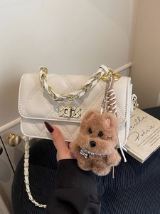 White quilted crossbody bag with gold chain strap and cute plush dog pendant charm