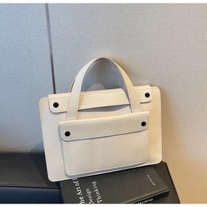 Dettaglio borsa a mano crema minimalista con tasca a due bottoni su sgabello nero
