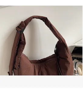 Detail of coffee-colored quilted shoulder bag with wide adjustable strap and buckle
