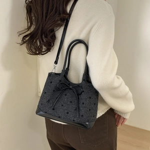 Close-up of stylish polka dot tote bag with black bow detail and leather trim
