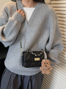 Quilted black crossbody bag with gold chain strap and brown puppy bag charm