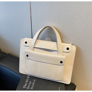 Dettaglio della borsa beige minimalista con tasca frontale e bottoni neri decorativi