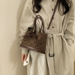Detail of tweed tote bag with bow embroidery and brown leather trim on a model