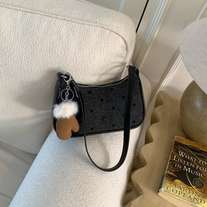 Detailed close-up of a polka dot shoulder bag with a mini glove charm on a cozy sofa