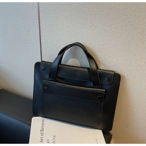 Dettaglio della borsa nera in ecopelle con rivetti circolari e manici dal design raffinato