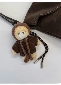 Detail of plush bear bag charm wearing a brown knit sweater with a red heart embroidery
