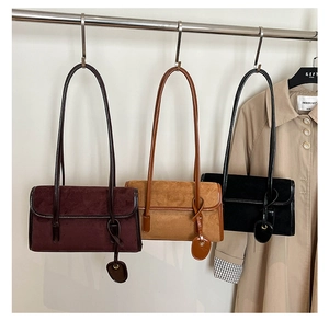 Detailed view of suede shoulder bags in burgundy, brown and black with matching charms