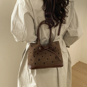 Detail of polka dot embroidery and large bow on brown fabric tote with leather strap
