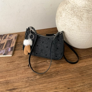 Detailed top view of polka dot pattern shoulder bag with faux fur pompom charm