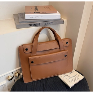 Dettaglio di una borsa business in pelle marrone con tasca a patta e fibbia nera decorativa