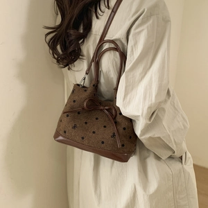 Detail view of brown polka dot tote bag with leather bow accent and stitching texture