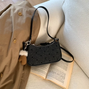 Close-up of polka dot fabric texture on underarm bag with plush glove charm