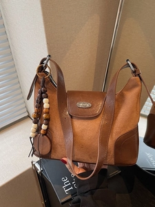 Vintage brown dumpling shoulder bag in matte suede with beaded tassel and metal logo
