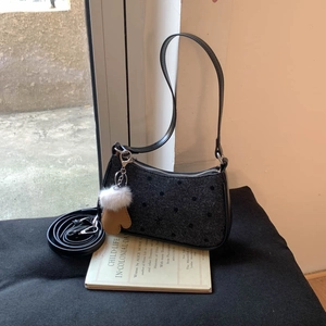 Close-up of black polka dot underarm bag with silver zipper and plush charm accessory