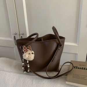 Close-up of dark brown lychee grain tote bag with cute white plush dog charm