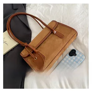Detailed close-up of brown suede underarm bag with leather trim on white linen