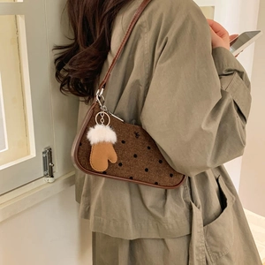 Detail of retro polka dot shoulder bag with brown leather trim and cute glove charm