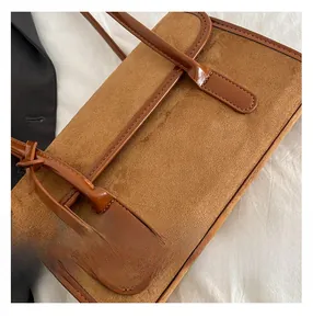 Close-up of brown suede and smooth leather stitching on the chic caramel shoulder bag