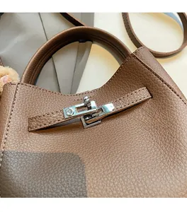 Detail of brown litchi pattern leather handbag with silver clasp and plush charm