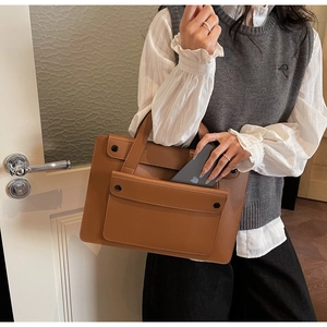 Dettaglio della borsa in pelle marrone con tasca frontale e chiusure in metallo nero
