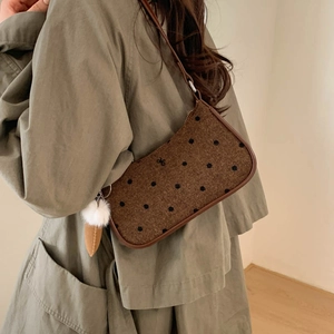 Polka dot woolen shoulder bag with black bow and white fur ball pendant detail