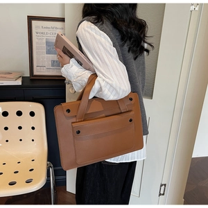 Detail showing high-quality brown leather texture and reinforced handle of this tote bag