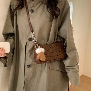 Close-up of brown polka dot shoulder bag with cute glove pendant and leather trim