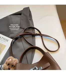 Detail of brown lychee leather handbag with silver lock and adjustable shoulder strap