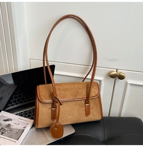 Detailed view of brown retro underarm bag with contrast textures beside a laptop