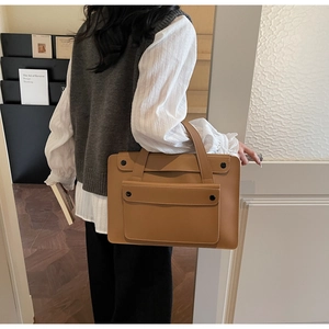 Dettaglio di una borsa in pelle marrone con tasca frontale a patta e fibbia in metallo