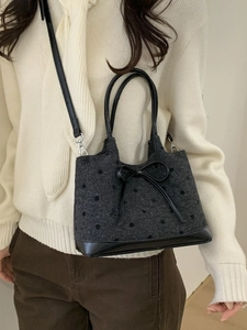 Retro grey tweed bucket bag with black polka dots and bow, worn as a crossbody by model