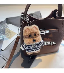 Close-up of a plush dog bag charm with a striped sweater on a brown textured leather bag