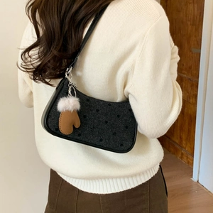 Polka dot underarm bag in wool fabric with leather trim and glove charm on a model