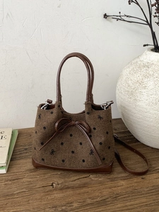 Vintage brown tweed tote bag with black polka dots and leather bow detail on wood surface