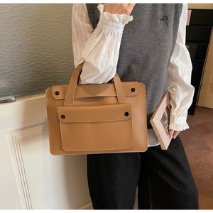 Dettaglio della borsa tote in pelle PU cammello con tasca a patta e fibbia nera tonda