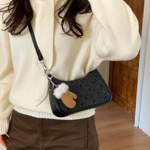 Close-up of women's polka dot tweed underarm bag with a cute plush glove charm detail