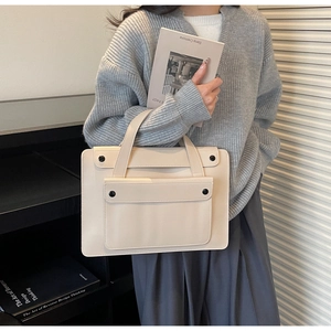 Dettaglio di borsa beige con tasca a patta frontale e chiusura con bottone nero rotondo