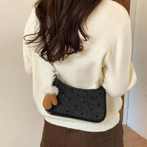 Detail of grey polka dot tweed shoulder bag with a cute brown glove charm