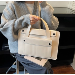 Close-up of creamy white leather tote bag with contrasting black button fasteners
