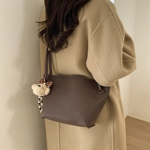 Detail of dark brown pebble leather crossbody bag with a cute plush bear charm