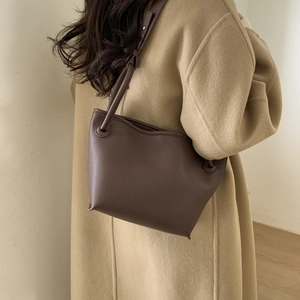 Minimalist dark brown lychee grain leather bucket bag showing unique curved top edge
