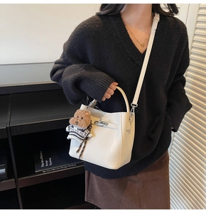 Detailed shot of white leather bucket bag with silver lock and bear charm accessory