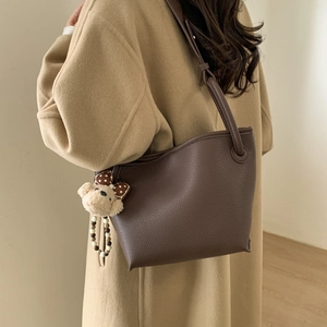 Detail of dark brown lychee textured tote bag with cute plush bear charm on a crossbody strap