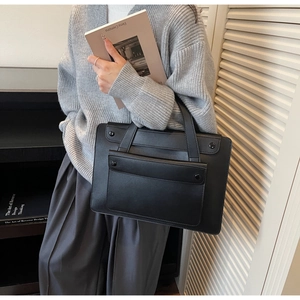 Detail of a black large-capacity vintage tote bag featuring a practical front flap pocket