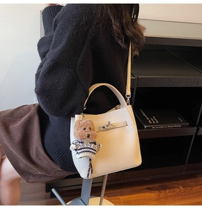 Detail of cream lychee leather bucket bag with silver turn-lock and teddy bear charm