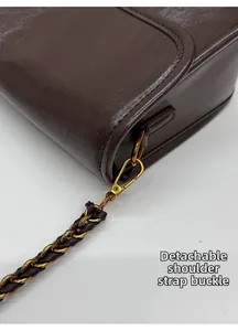 Détail de la boucle dorée amovible sur le sac à bandoulière en cuir marron vintage