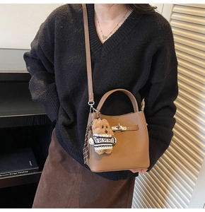 Brown lychee leather handbag with silver lock and teddy bear charm on model
